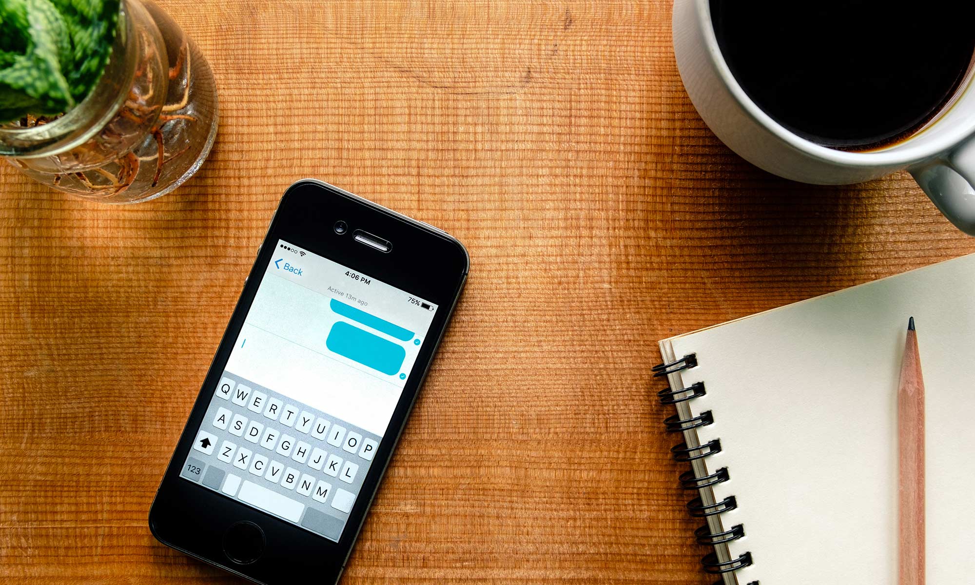 iPhone on wooden table with coffee and notepad